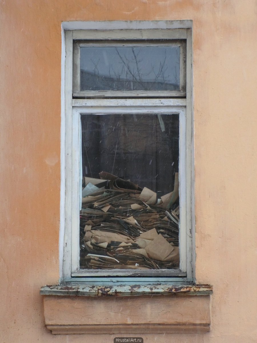 Старое окно, вид с улицы, до середины своей высоты заполнено бумажными листами.