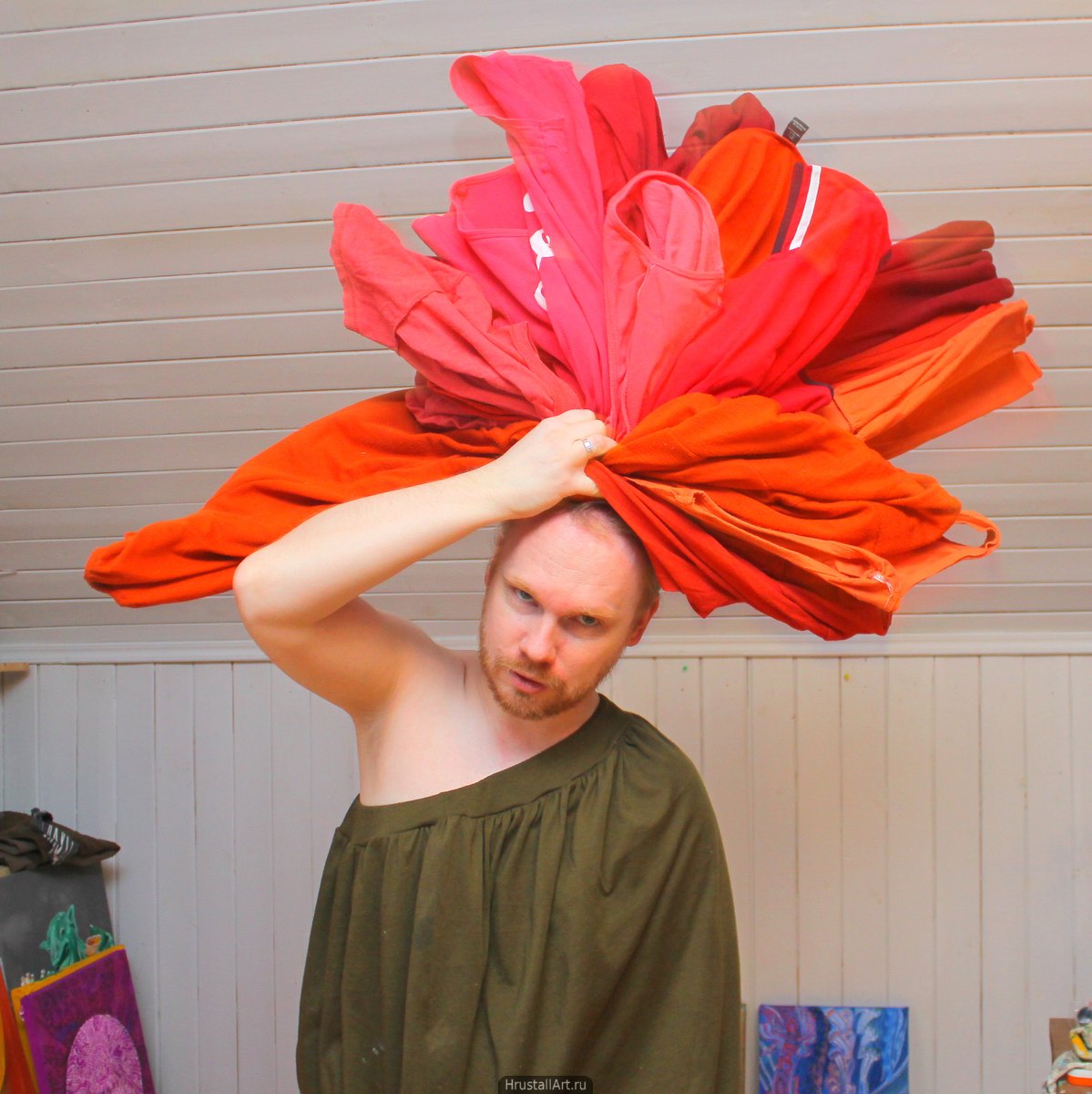 Парень с кипой красного белья на голове, изображает распустившийся цветок.