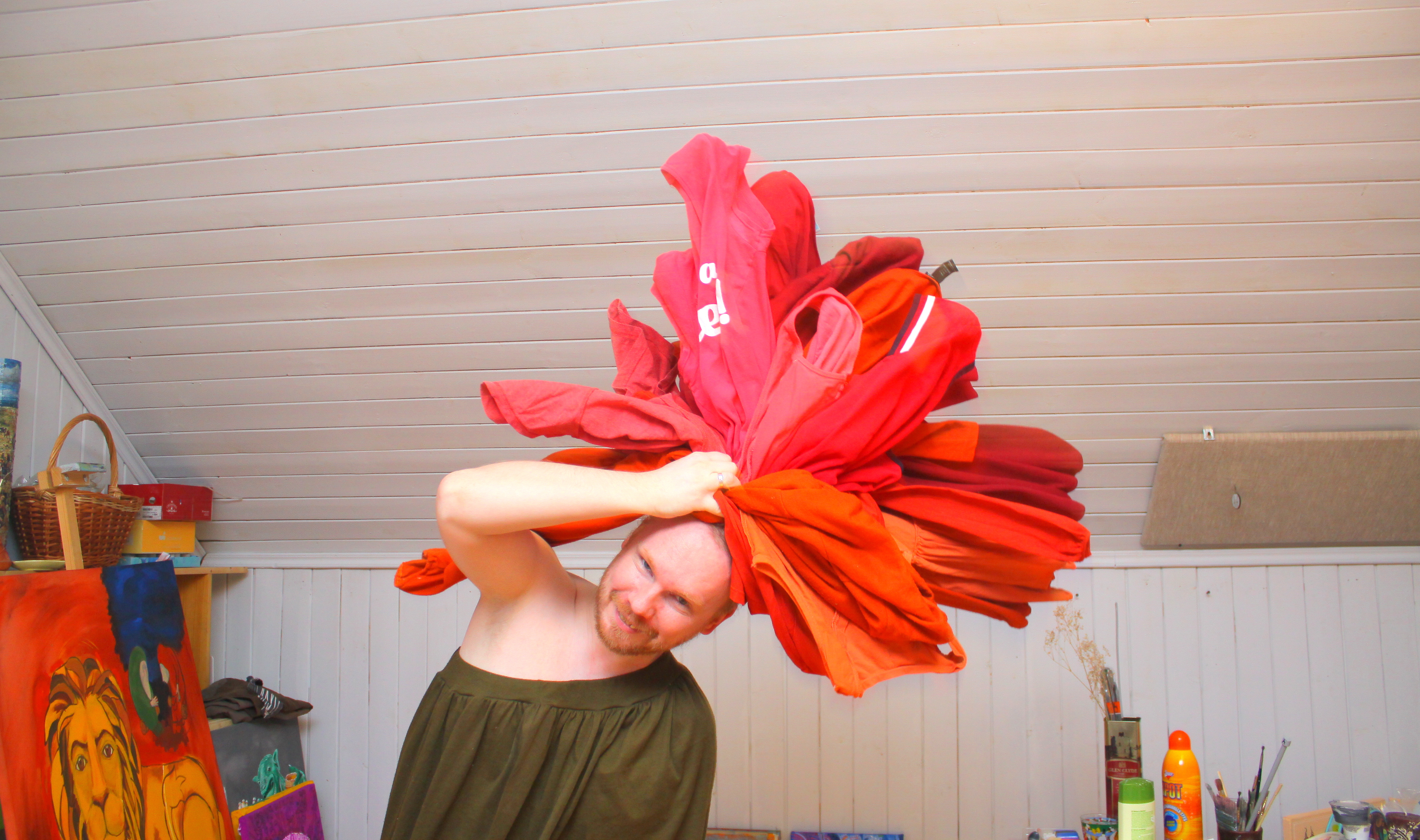 Парень с кипой красного белья на голове, изображает распустившийся цветок.