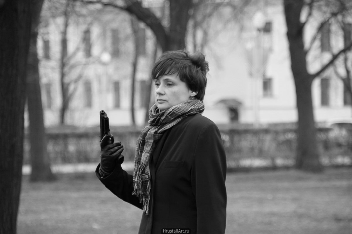 Фото, девушка с пистолетом в руке, в холодном парке погружена в собственные мысли.