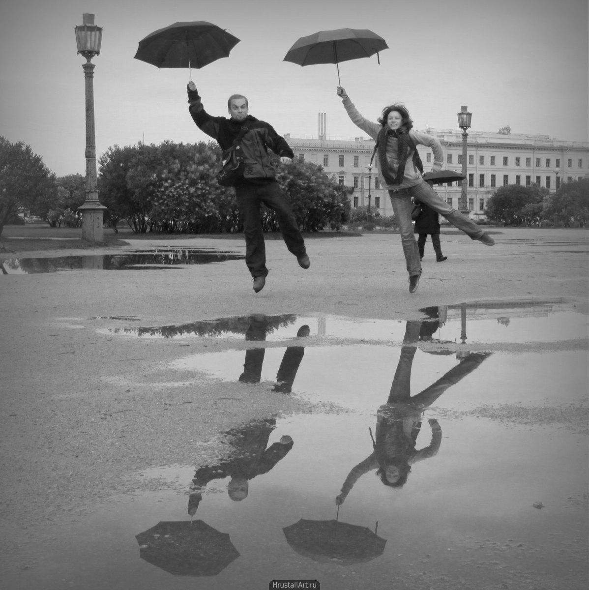 Фотография, весёлая пара с зонтиками театрально прыгает на Марсовом поле в Петербурге.
