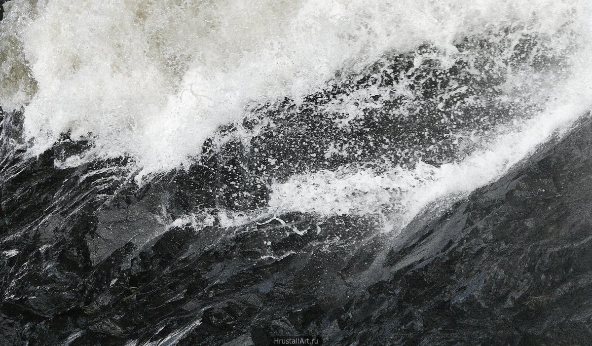 Фотография, фактура: тёмные камни и белые летящие брызги воды.