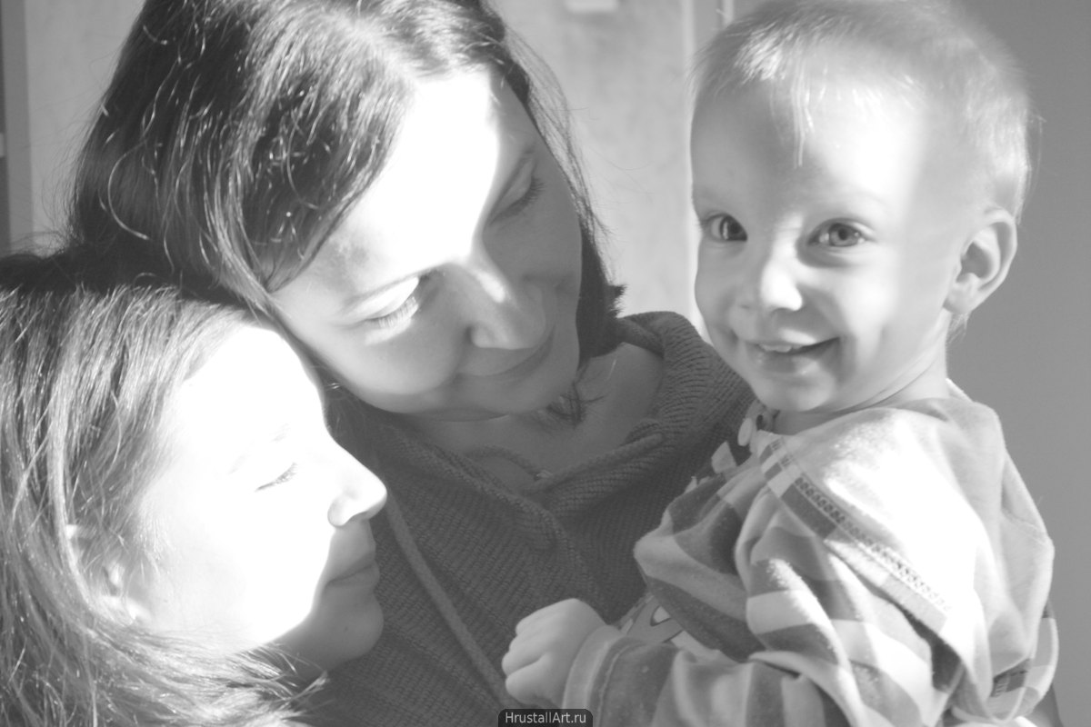 Фото в высоком ключе, мать с двумя детьми, маленький сын очаровательно и открыто улыбается, солнечный свет заливает лица его матери и сестры создавая ощущения что источник света прямо в ребёнке.