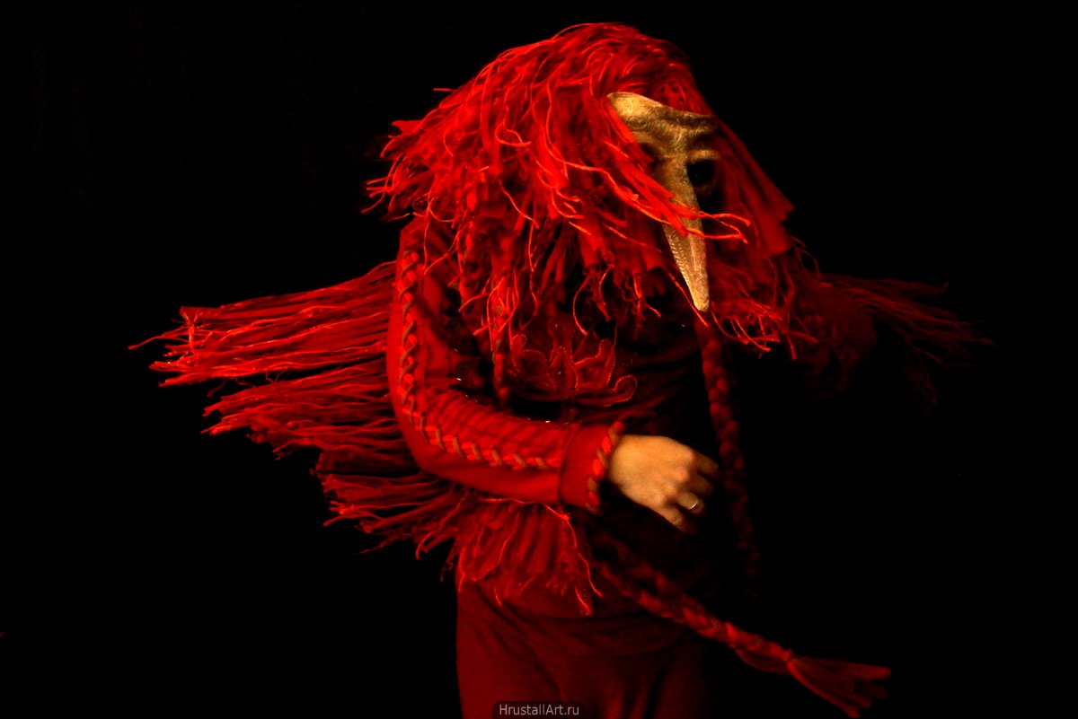 Персона в красном шаманском костюме птицы динамично кружится.