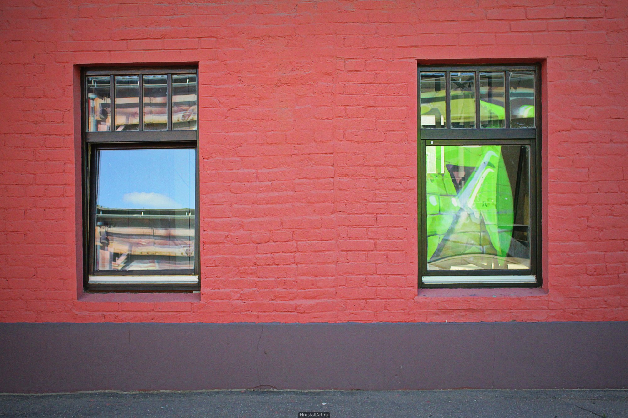 Яркие зеленые и синие отражения в окнах на красной стене.